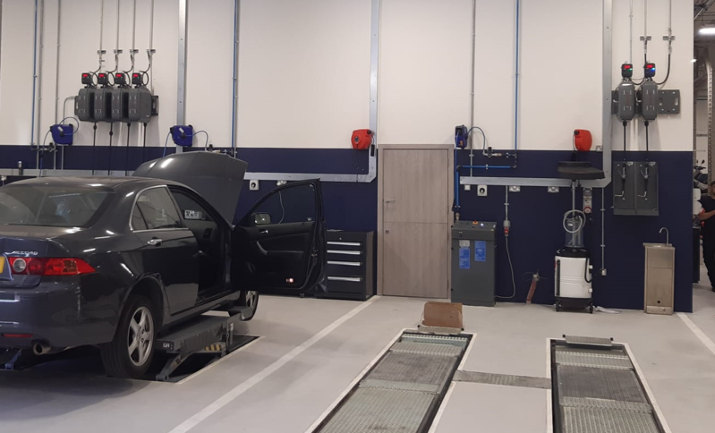 Professional mechanical workshop with scissor lifts and overhead lubrication systems.