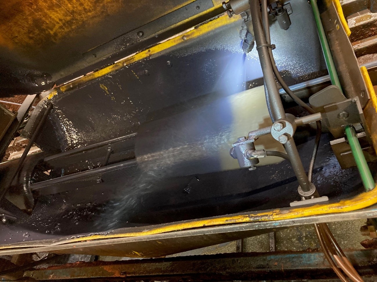Industrial spraying system applying an atomized coating onto a rotating metal roller inside a process cabin