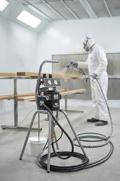 Worker using Fine-Jet airless spray system for precision coating in industrial finishing applications