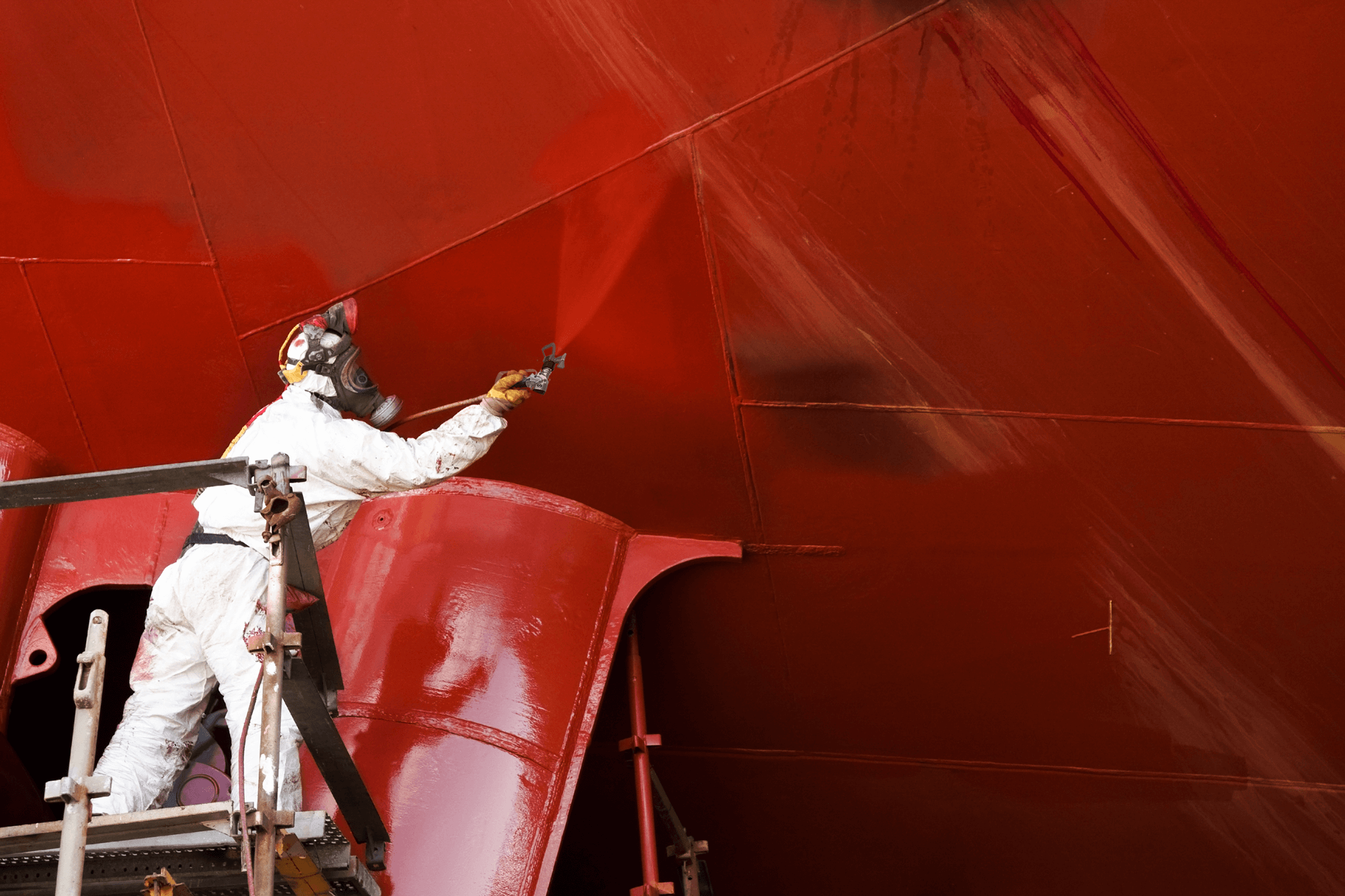 Close-up of airless spray coating on large industrial surface with high-performance paint